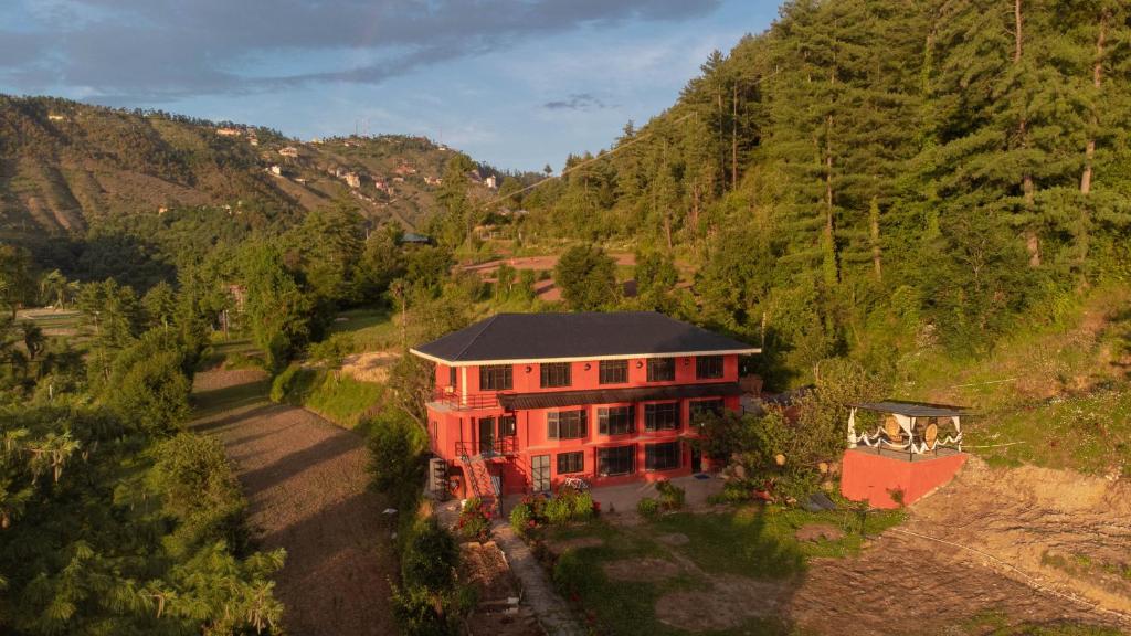 an aerial view of a red house in a mountain at Minimalist : An Eco Farmstay in Nāldera