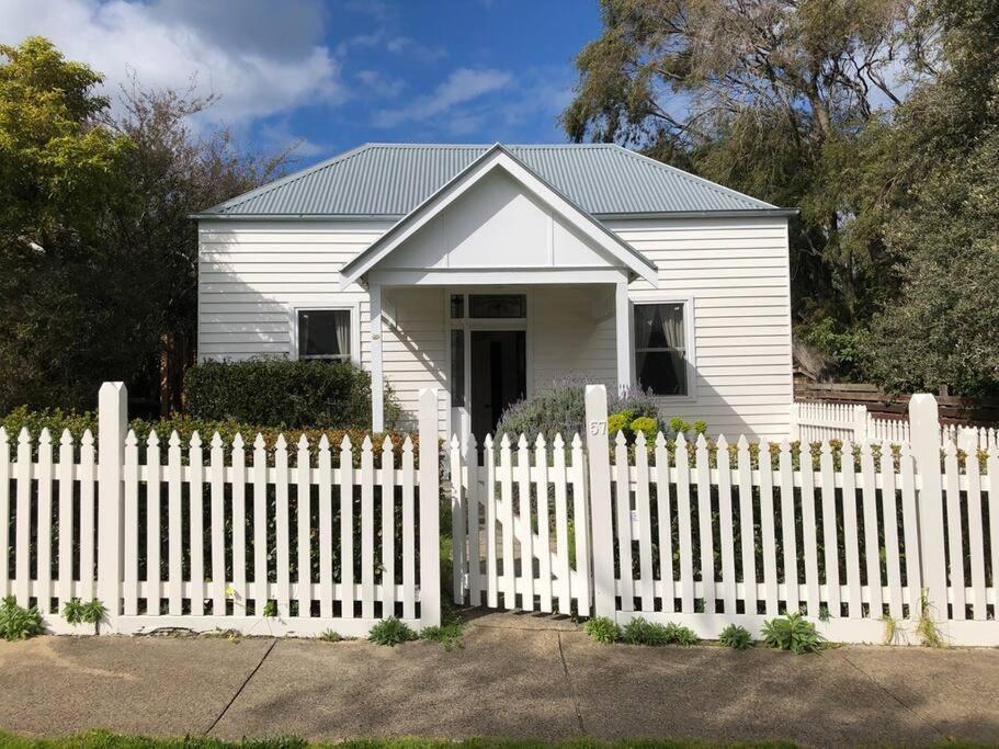 a white house behind a white picket fence at Beach House of Queenscliff in Queenscliff