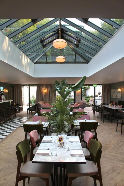 a restaurant with tables and chairs and a glass ceiling at Lydiard Park Hotel in Swindon