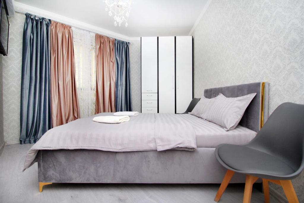 Un dormitorio con una cama grande y una silla. en Elif Towers Residence 1BR great city view & drinking water, en Almaty