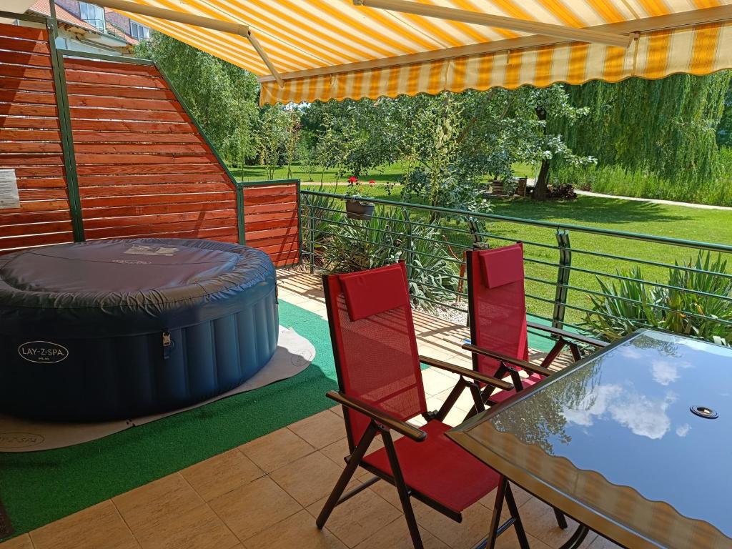 a patio with a table and chairs and a barrel at Csiribá Apartman in Cserkeszőlő