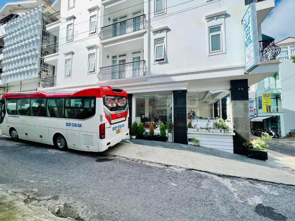a red and white bus parked in front of a building at Dalat ECO Hotel 2 in Da Lat
