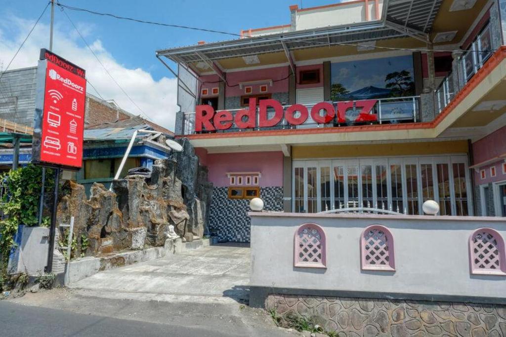 ウォノソボにあるRedDoorz near Desa Wisata Tambi Diengのピンクの建物前の赤い出入り口看板