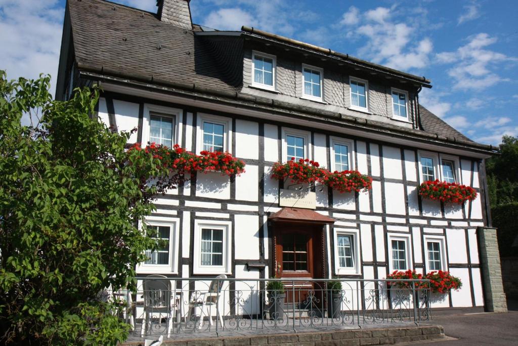 a white and black building with red flowers on the windows at Landhaus Gnacke in Schmallenberg