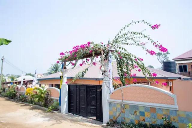 Un edificio con un cancello con dei fiori sopra di Nana Adu Guest House a Koforidua