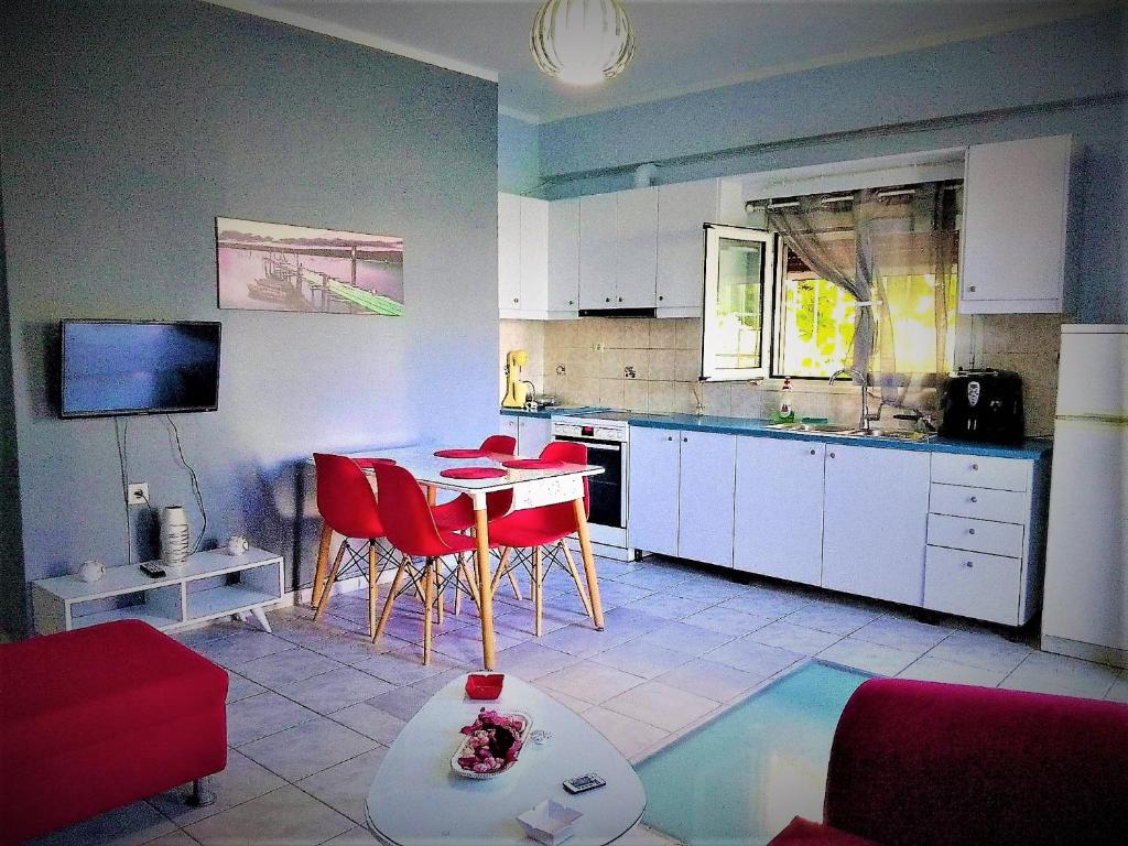 uma cozinha com uma mesa e cadeiras vermelhas num quarto em Rafaela’s House em Skiathos