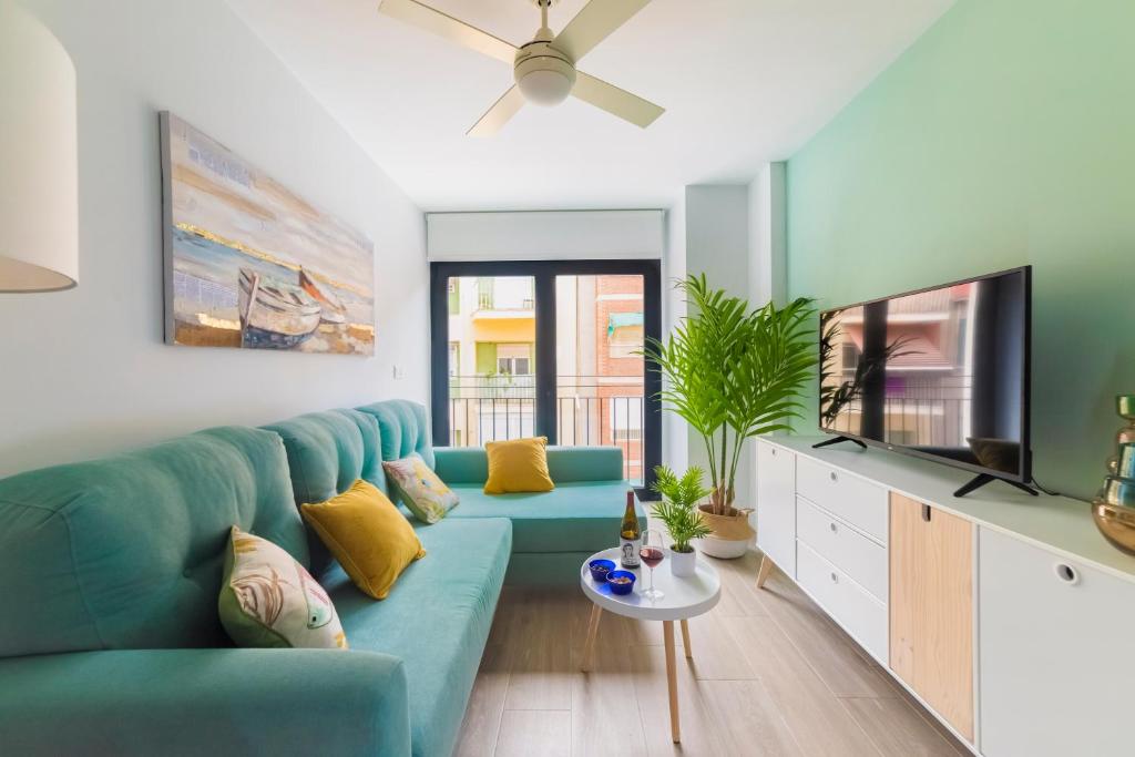 a living room with a blue couch and a tv at Bretón 17- Apartamentos con piscina climatizada en Alicante centro in Alicante