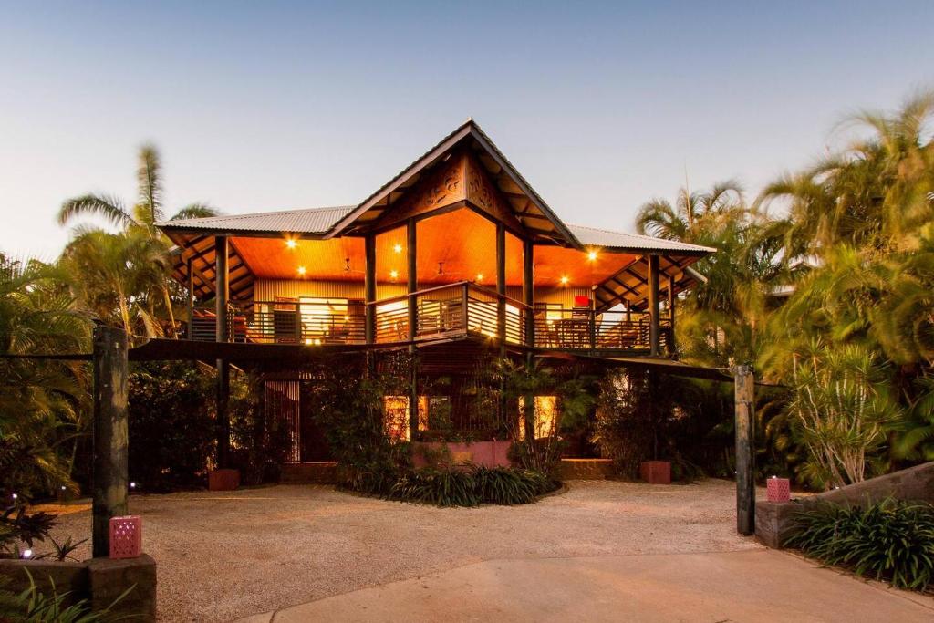 a large house with a balcony and palm trees at Asrama Broome in Broome