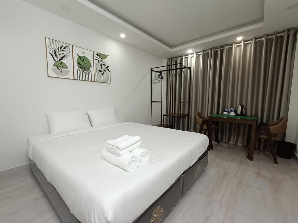 Un dormitorio con una gran cama blanca y una mesa en Best Studio Room Near Ben Thanh Market, en Ho Chi Minh