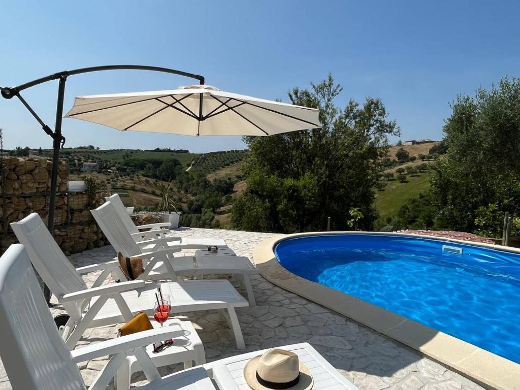 - Piscina con sillas, mesa y sombrilla en Casa Sergio, en Colonnella