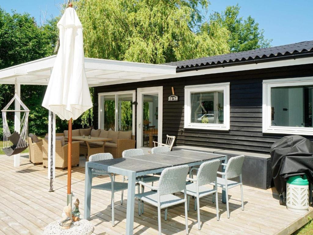 eine Terrasse mit einem Tisch, Stühlen und einem Sonnenschirm in der Unterkunft Holiday home Højby III in Højby