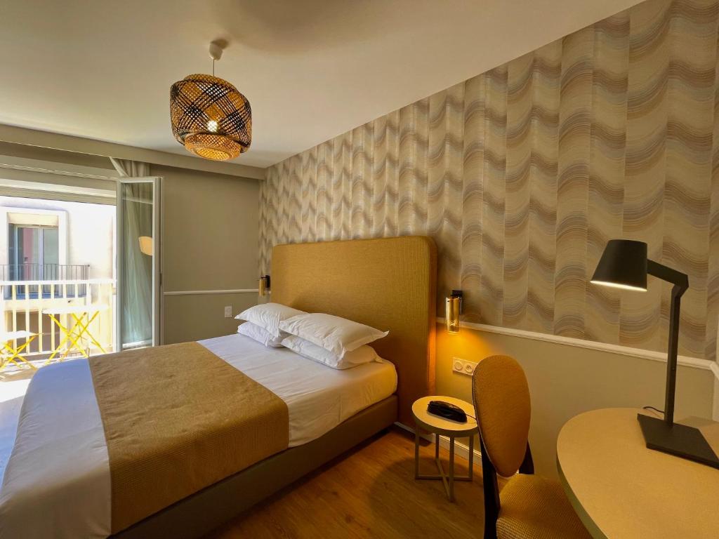 カルヴィにあるHotel Restaurant Christophe Colombのベッドルーム(ベッド1台、テーブル、ランプ付)