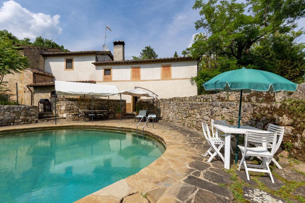 einen Pool mit einem Tisch, Stühlen und einem Sonnenschirm in der Unterkunft Casale Mulin Bianco in Monteriggioni