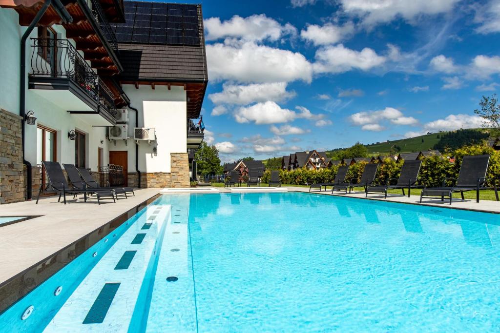 a swimming pool with chairs and a house at Hotel Bystra in Białka Tatrzańska