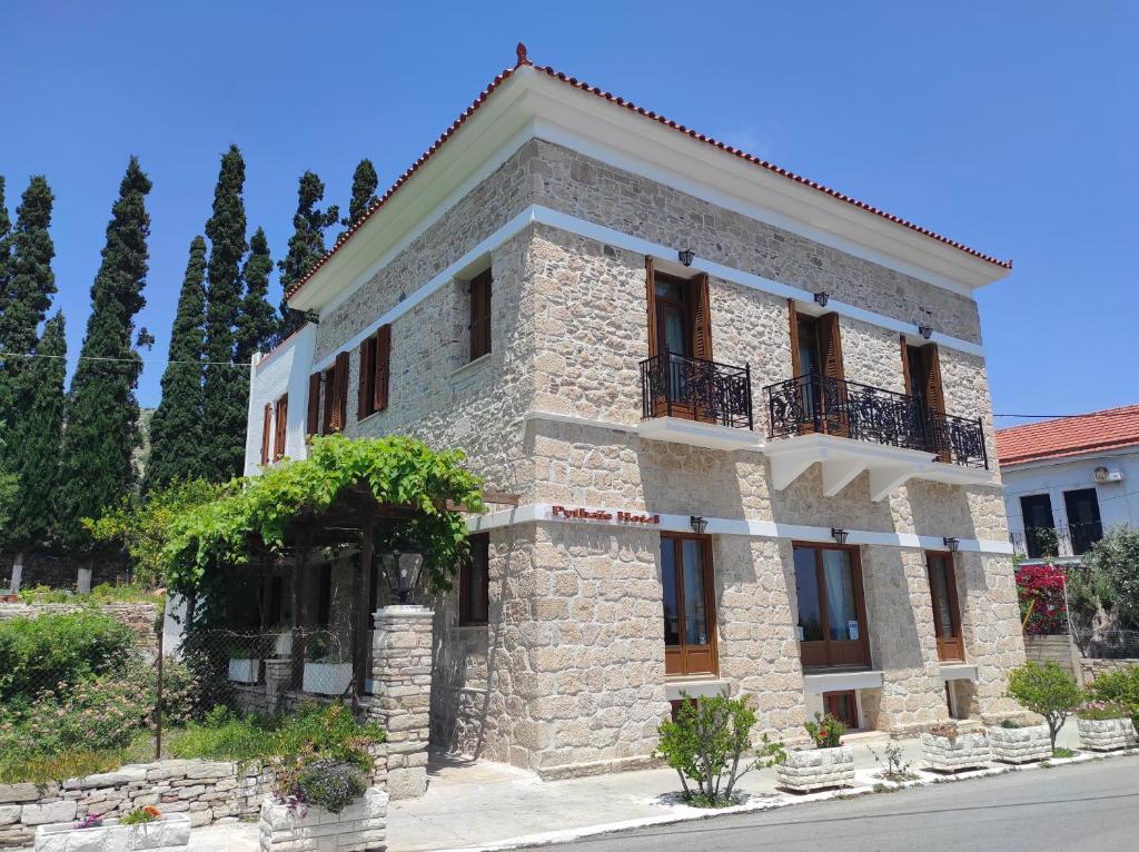 - un bâtiment en pierre avec un balcon dans une rue dans l'établissement Pythaïs Hotel, à Pythagoreio