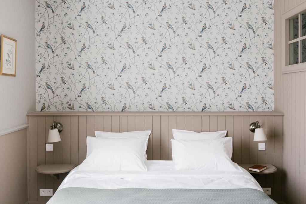 - une chambre avec un lit et un papier peint floral dans l'établissement La Maison d’Hôtes, à Silly