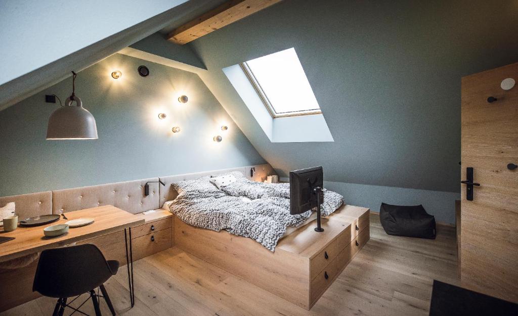 Schlafzimmer mit einem Bett und einem Schreibtisch mit einem TV in der Unterkunft Rousa little guesthouse Cosy Sky in Oberrasen