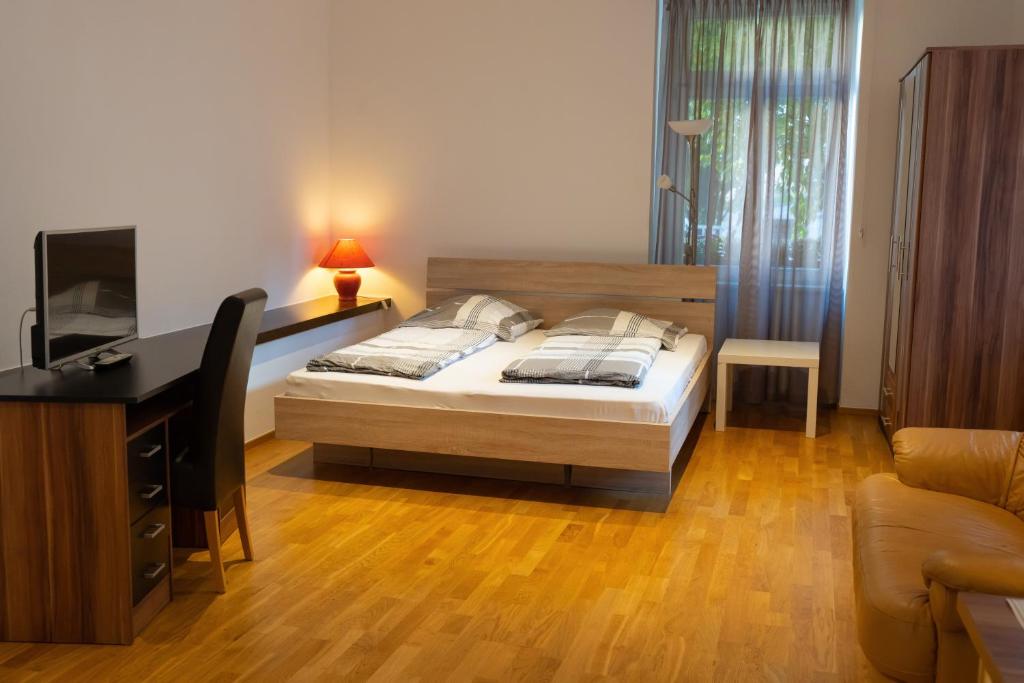 a bedroom with a bed and a desk and a television at Ferienwohnung Baden Baden in Baden-Baden
