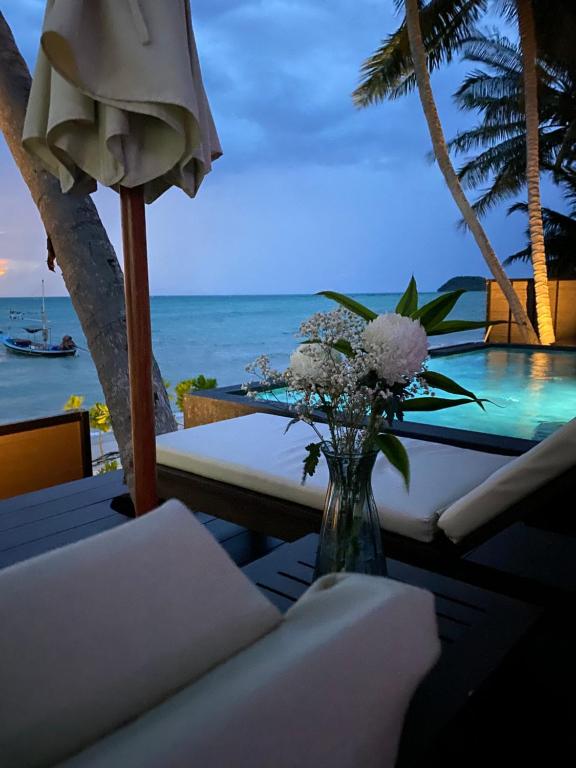 un vase de fleurs assis sur une table avec l'océan dans l'établissement Villa Manolo, à Ban Bang Makham