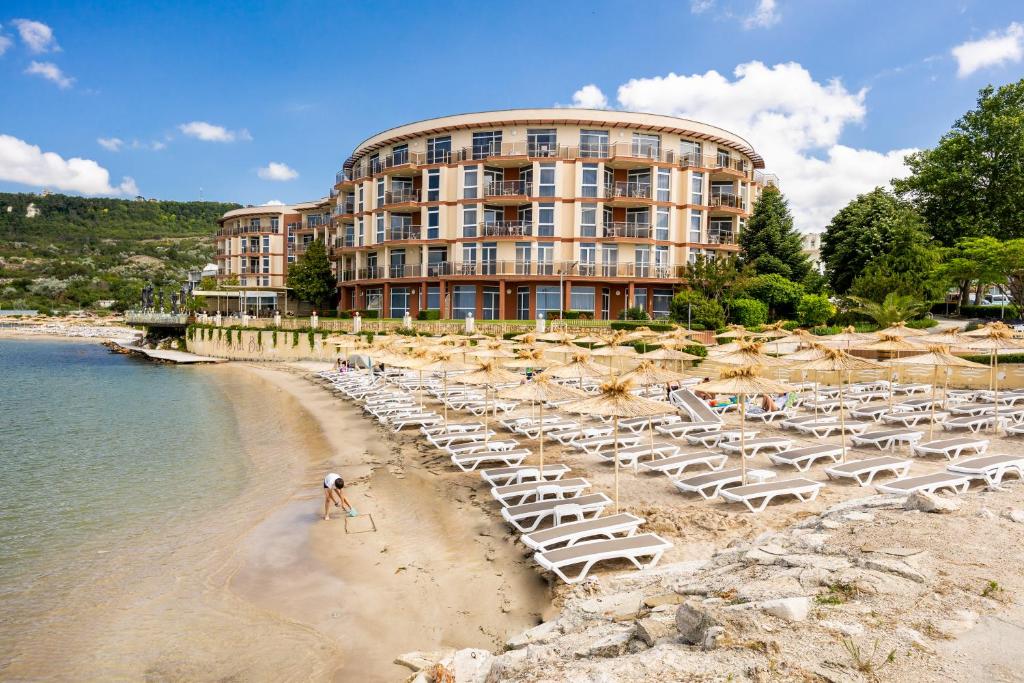 um hotel com uma praia com cadeiras e um edifício em Royal Bay Resort - All Inclusive and Free beach accsess em Balchik