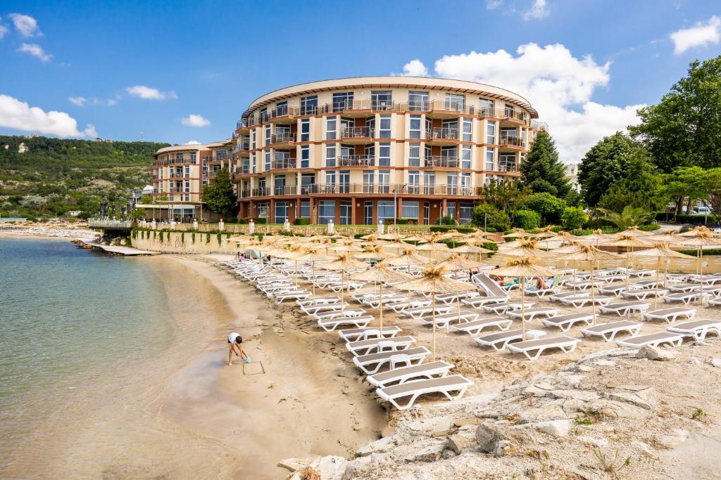 ein Hotel mit einem Strand mit Stühlen und einem Gebäude in der Unterkunft Royal Bay Resort - All Inclusive and Free beach accsess in Baltschik