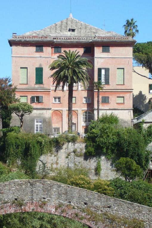a large pink building on a hill with a palm tree at Hotel Villa Bonera in Genoa