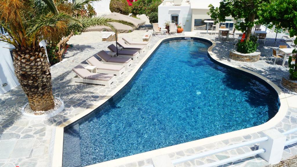 a swimming pool with chaise lounge chairs and a swimming poolvisorvisor at Petali Village Hotel in Apollonia
