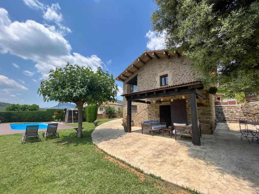 a stone house with a patio and a pool at Masia with pool and beautiful views near Girona in Girona