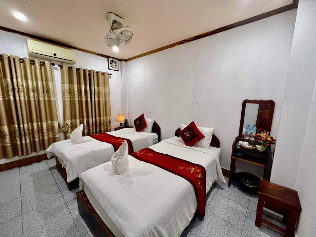 ein Hotelzimmer mit 3 Betten und einem Spiegel in der Unterkunft Nocknoy Lanexang Guest House in Luang Prabang