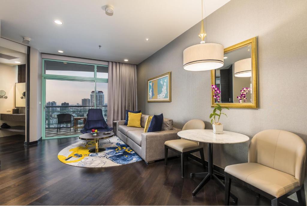 a living room with a couch and a table at Chatrium Hotel Riverside Bangkok in Bangkok