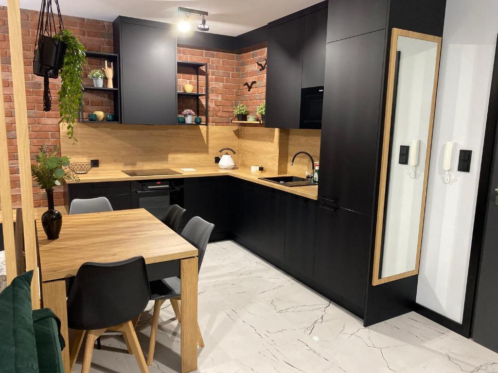 cocina con mesa de madera y armarios negros en Natura Resort "Bałtycki Sen", en Jastrzębia Góra