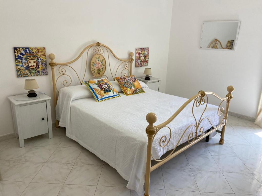 una camera da letto con un letto con cuscini e due tavoli di Case Gandolfo a Favignana