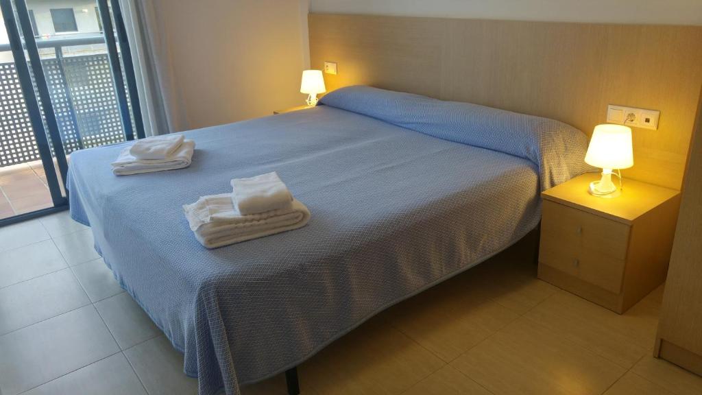 a bedroom with a blue bed with towels on it at Apartaments Las Carolinas in Sant Carles de la Ràpita