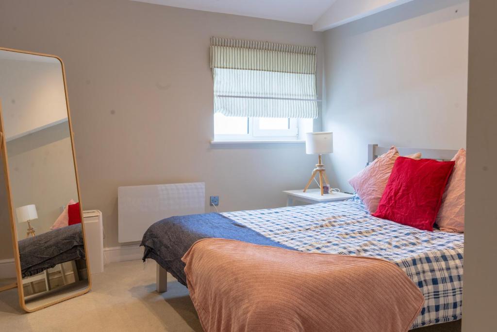 a bedroom with a bed with red pillows and a mirror at Beautiful New 2 Bed Flat - 5 August House in London