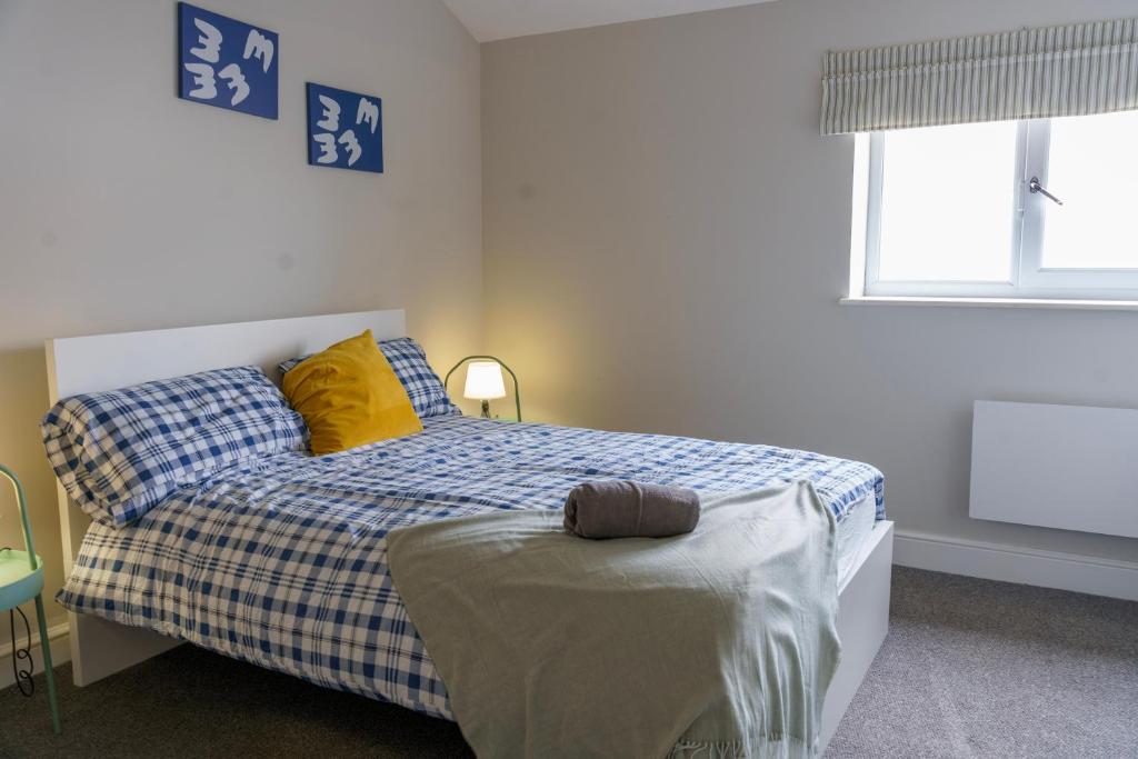 a bedroom with a bed with yellow pillows and a window at Stunning New 2 Bed Flat - 6 August House in London