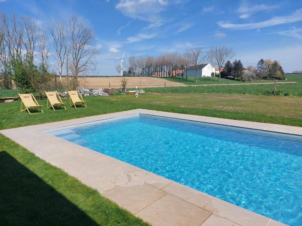 una piscina en un patio con 2 sillas en Double gite à la Campagne, en Gembloux