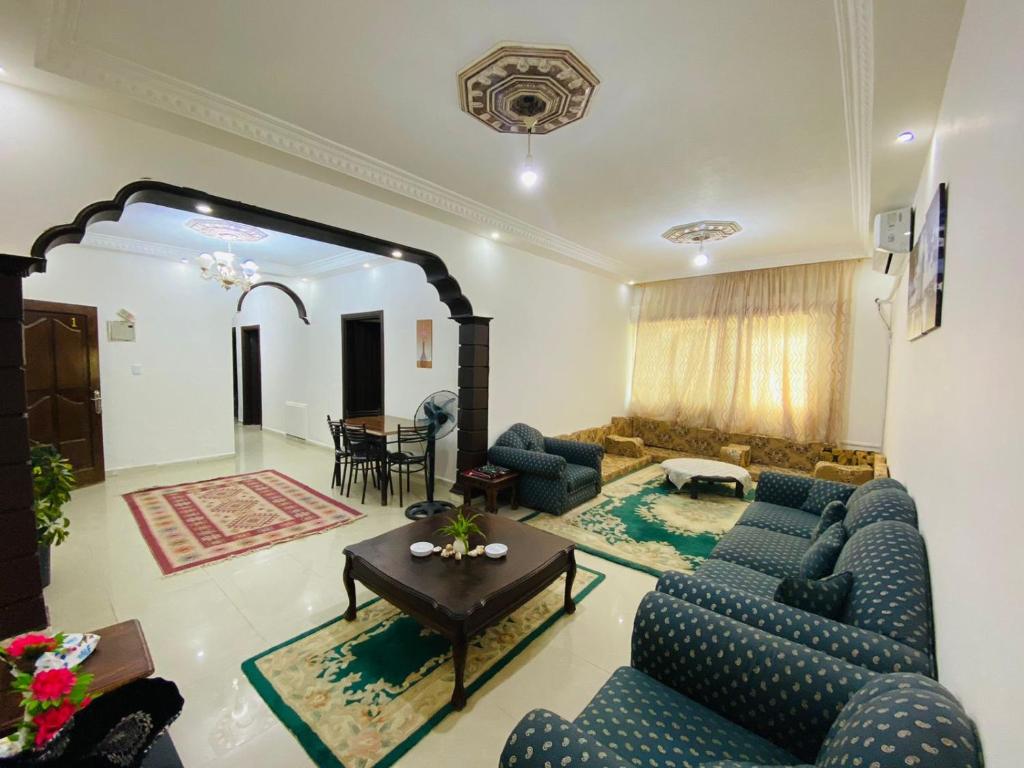 uma sala de estar com sofás azuis e uma mesa em شقه مفروشة الجبيهه em Amã