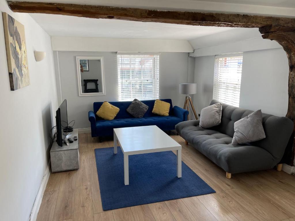 a living room with a blue couch and a table at Colchester Town Duplex Apartment in Colchester
