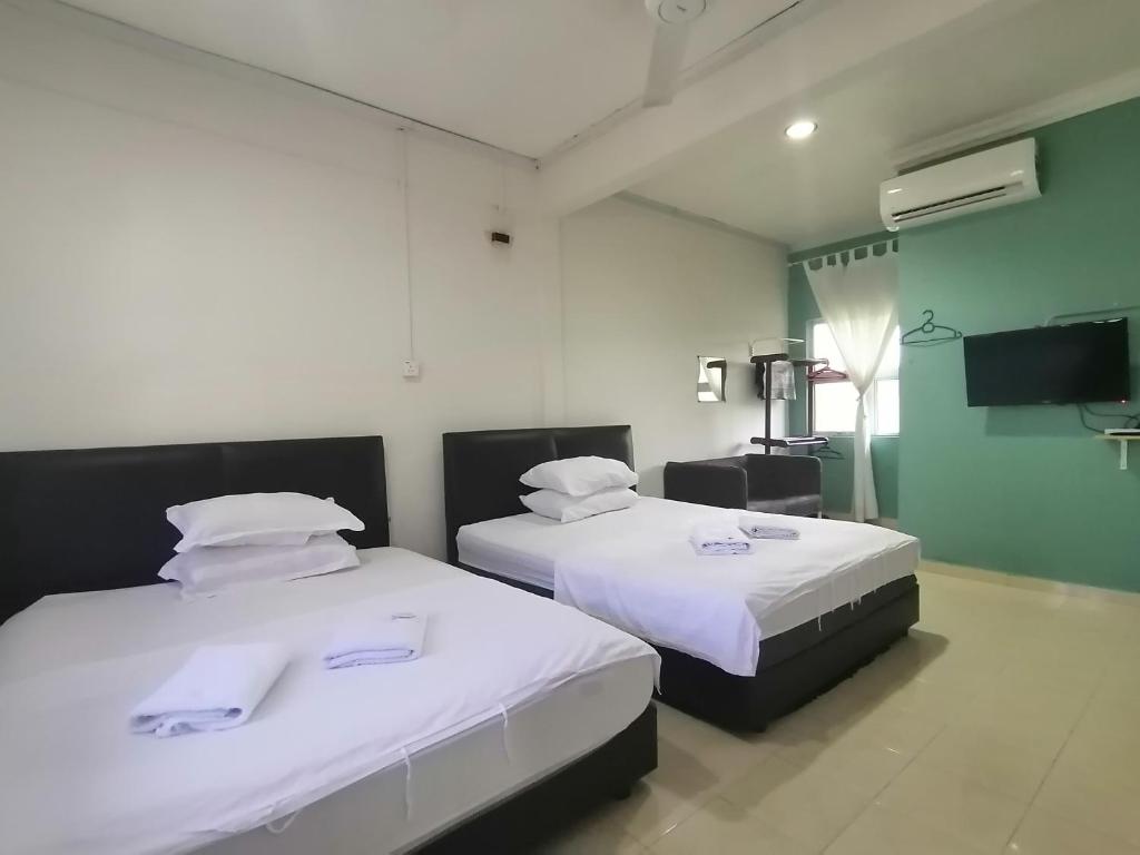 um quarto com 2 camas e lençóis brancos em FBS Inn Dungun em Dungun