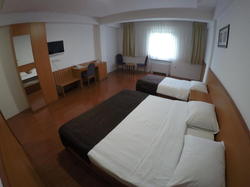 サラエボにあるHotel Sarajのベッド2台とデスクが備わるホテルルームです。
