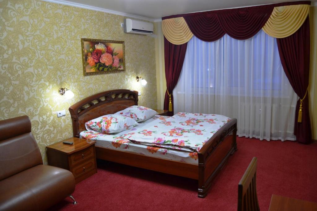 a bedroom with a bed and a chair and a window at Apartamenty-Absolut-Mira 72. in Nizhnekamsk