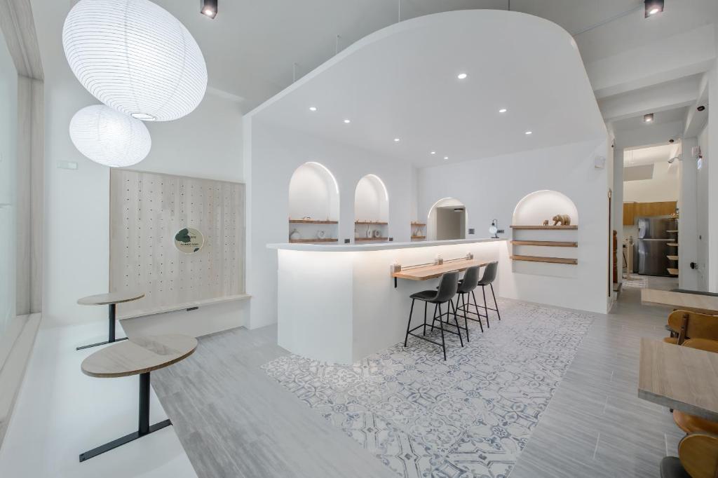 a white kitchen with a bar with stools and tables at Long Stay Here in Tainan