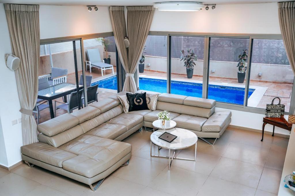 a living room with a large couch and a pool at O&O Group - Prestigious Beachfront Villa W Private Pool in Rishon LeẔiyyon