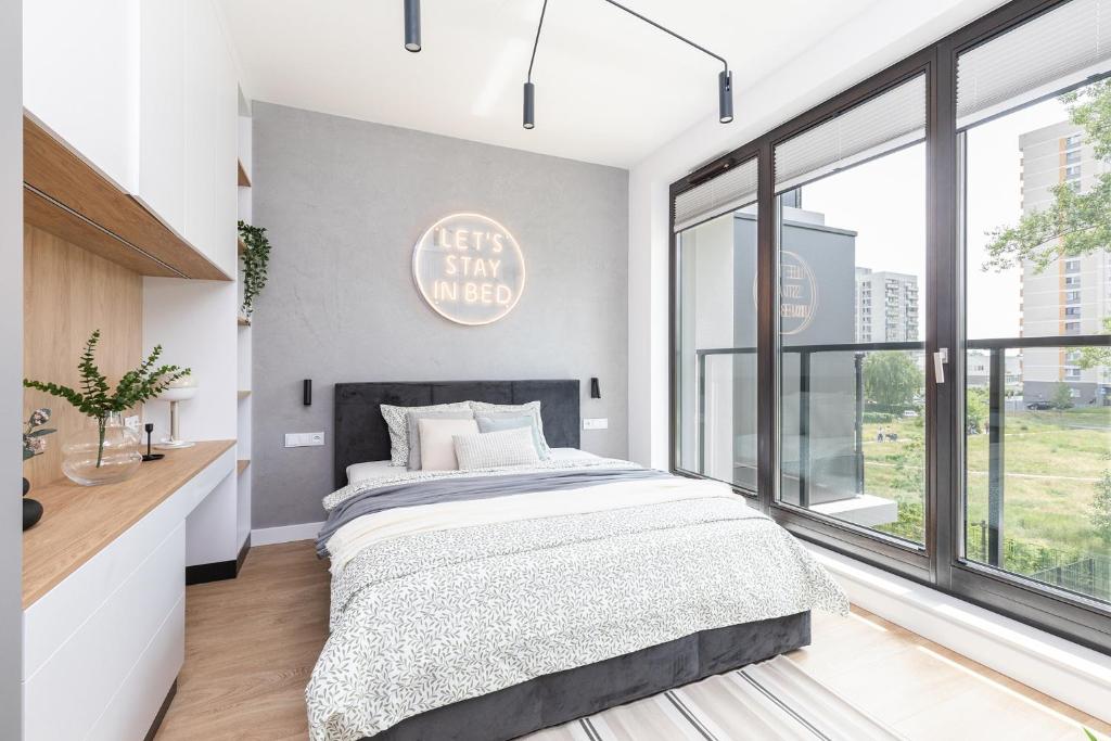 a bedroom with a large bed and large windows at SuperApart St. Augusta 71 in Warsaw