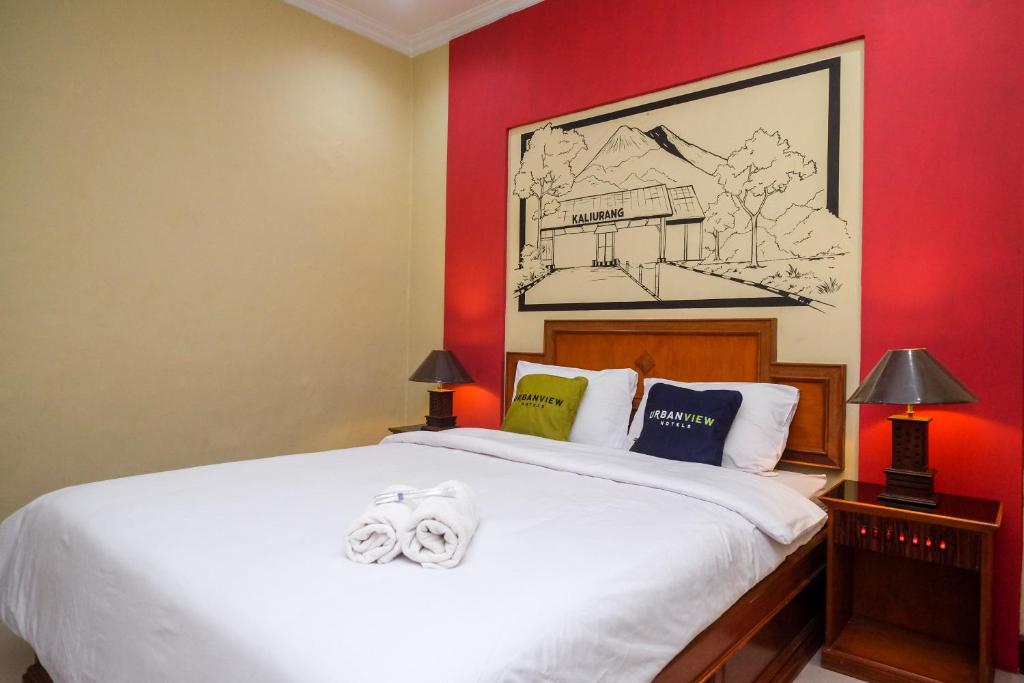 a bedroom with a white bed with red walls at Urbanview Hotel Syariah Wisnugraha by RedDoorz in Yogyakarta