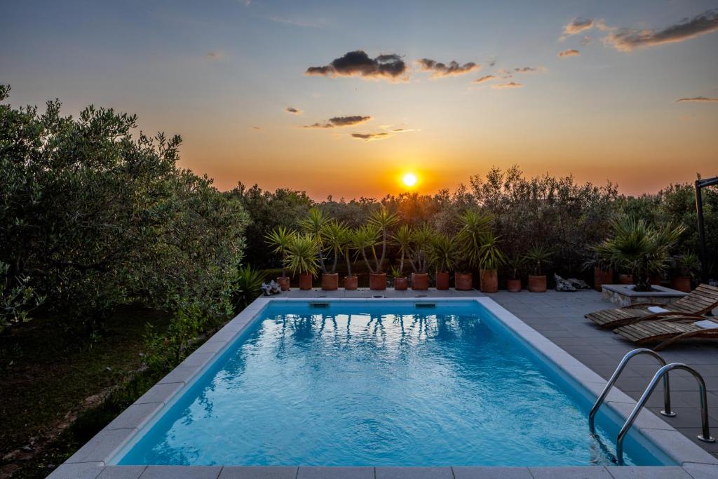 a swimming pool with a sunset in the background at Mai's Villa in Stari Grad