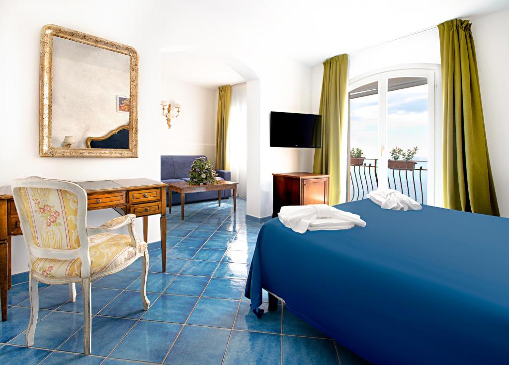 a hotel room with a blue bed and a desk at Hotel Villa Pandora in Maiori