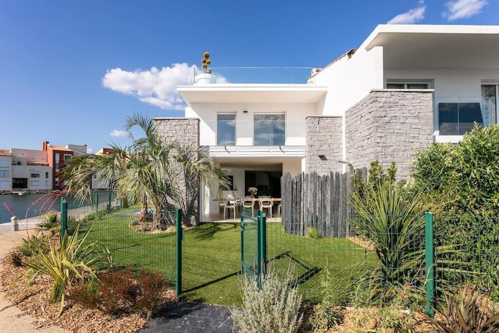 une maison blanche avec un jardin en face dans l'établissement Villa - Maison 10 pers - Cap d'agde - Cap Dream's - 4 Etoiles, au Cap d'Agde