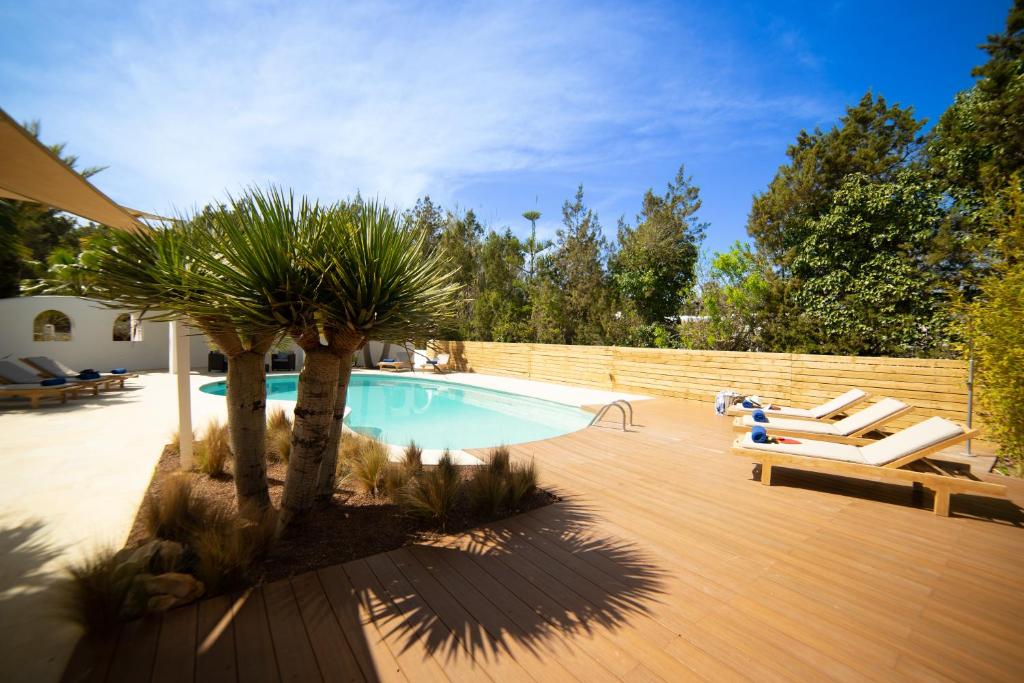 una piscina con una palmera junto a una terraza de madera en CAN MARTONA en San Antonio Bay