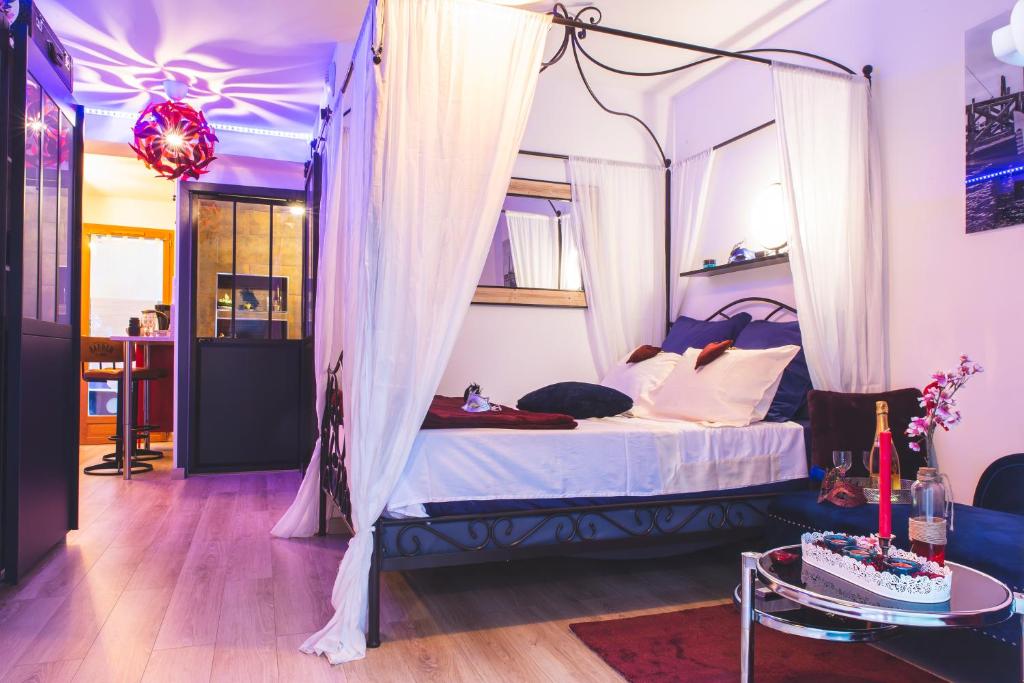 馬蒂格的住宿－Le Charme Martégal Suite/Spa，一间卧室配有一张天蓬床和一张桌子